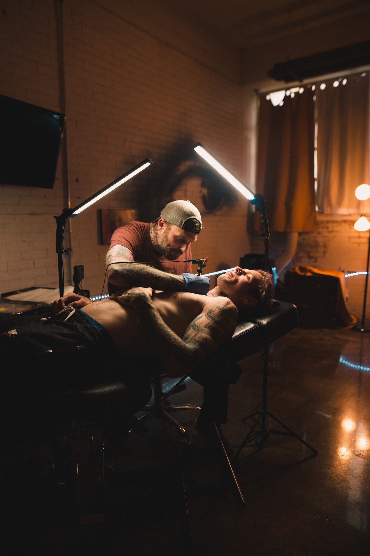 Tattoo artist complete a shoulder tattoo on a client laying on a black tattoo bed